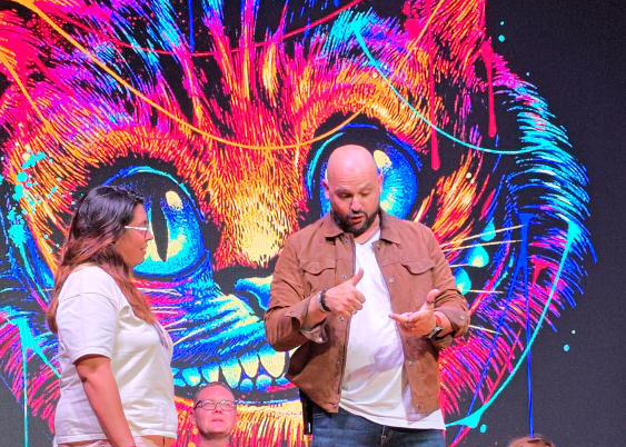 a man and woman on stage with a cat