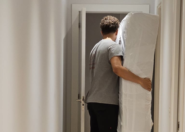 a man is moving a mattress in a hallway
