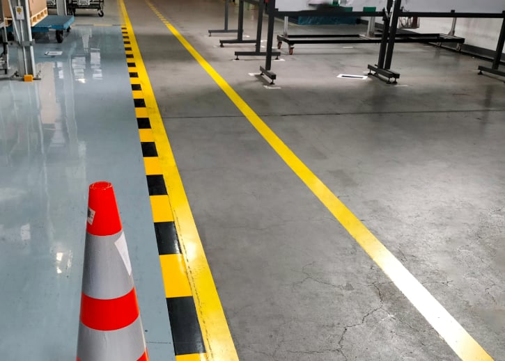 Trabajo de pintura industrial de una fabricas, tras pintar franjas amarillas y negras en el suelo.