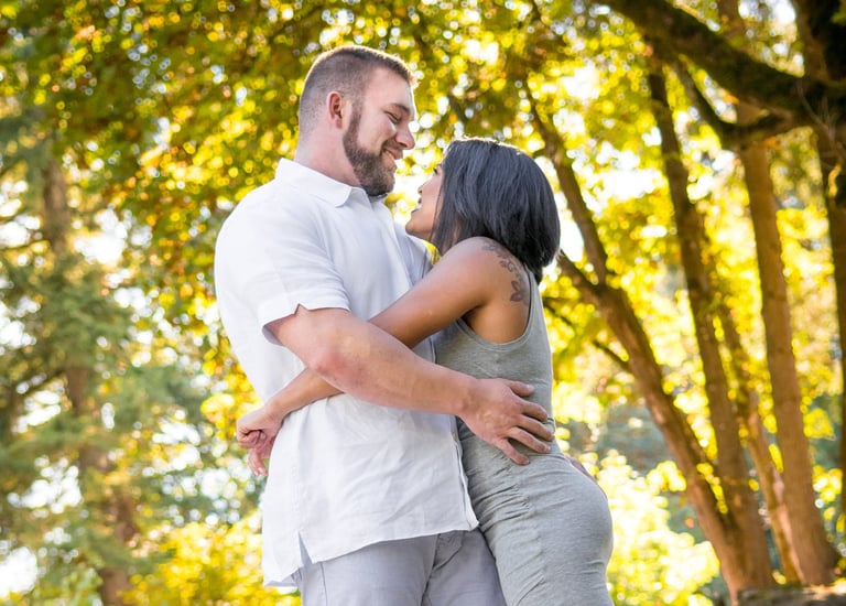a man and woman standing in front of a tree