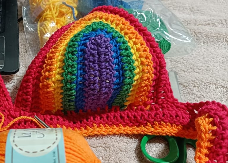 Bikini top de crochet arcoíris hecha a mano, confeccionada con hilo naranja.