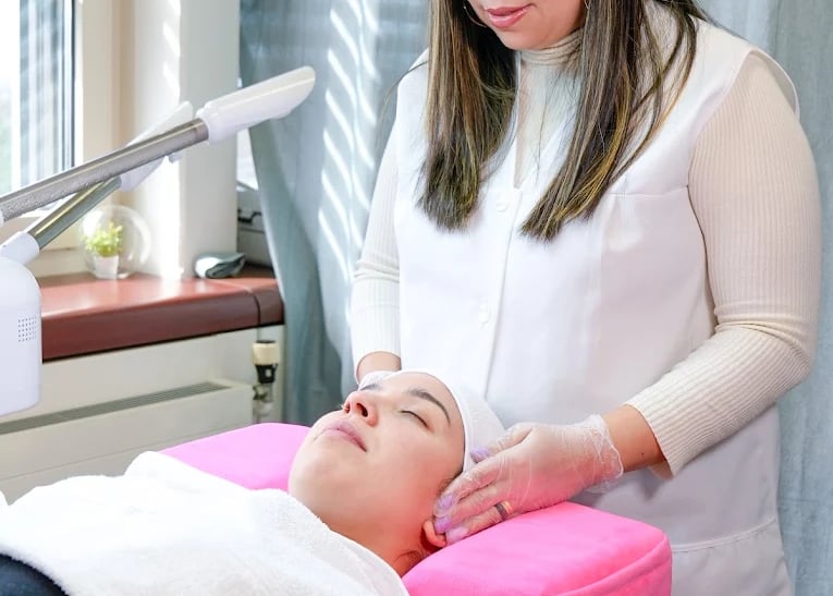 Professional esthetician performing a facial treatment and massage for a client at a skincare spa.
