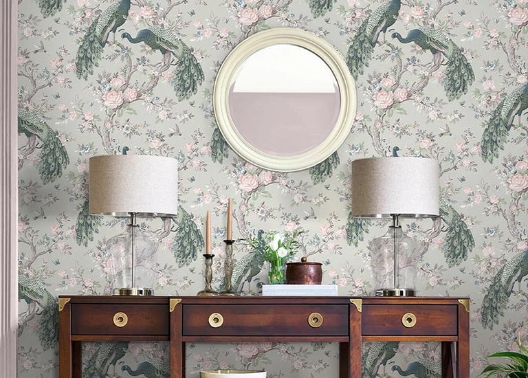 Elegant peacock floral wallpaper behind a dark wood console table with table lamps and a round mirror.