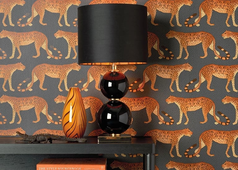 Modern interior featuring leopard print wallpaper with a black table lamp and stacked coffee table books.