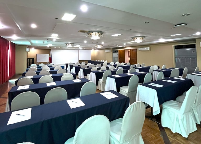 a meeting room with several tables and chairs and a projector for business and government events