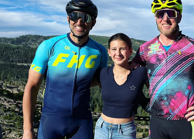 Two men cyclists posing with a girl in the outdoors