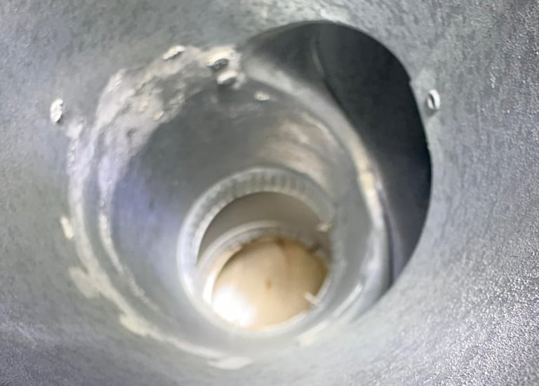 A view from inside a dirty and worn metal chimney flue, highlighting the need for a professional cleaning and inspection by R