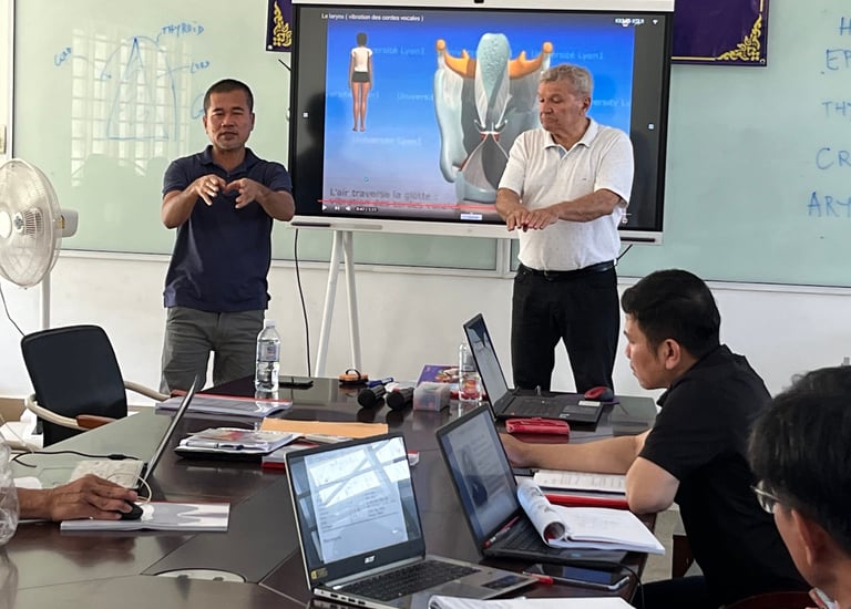 a group of people sitting around a table with laptops