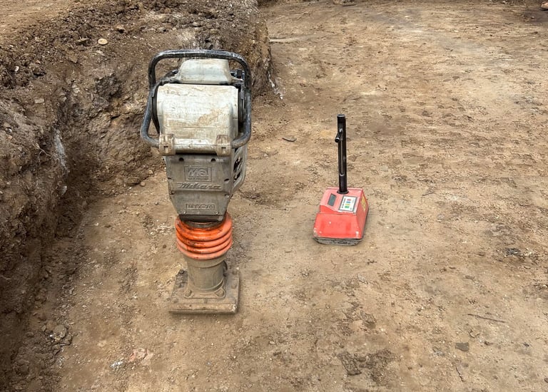 Technician performing field compaction testing on graded soil