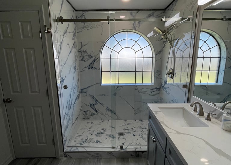 Modern master bathroom featuring a marble walk-in shower with glass doors and a double vanity.