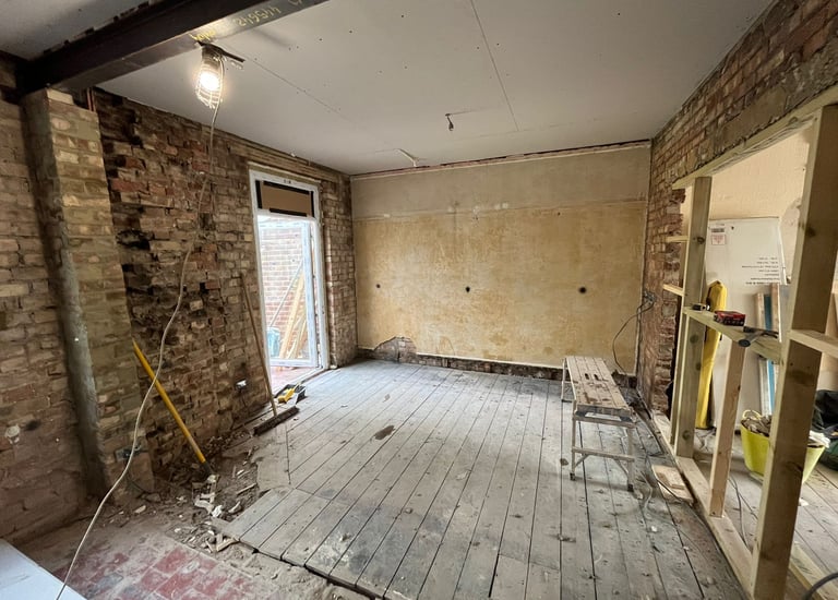 a room with a wooden floor and a brick wall in need of renovation