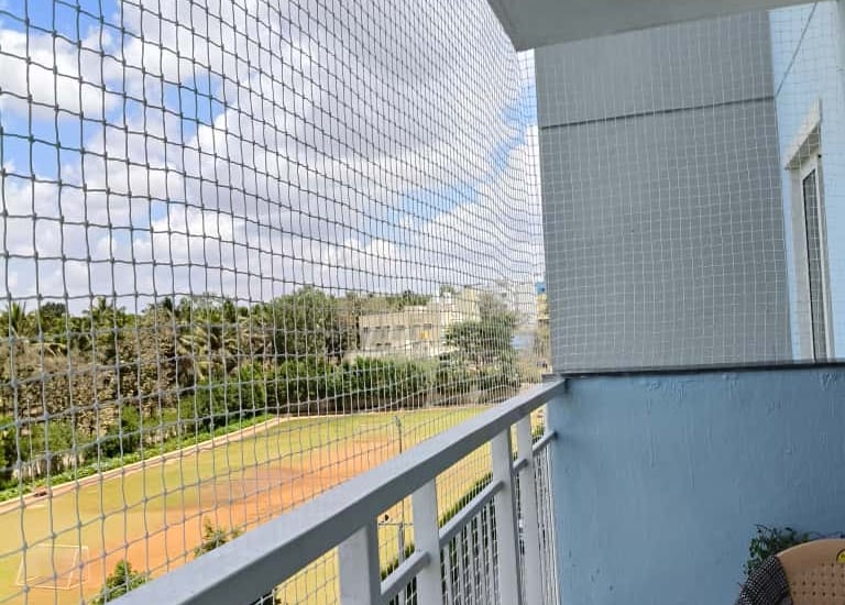 Close-up of a sturdy pigeon net securely fitted on a balcony railing in SHSR Layout.