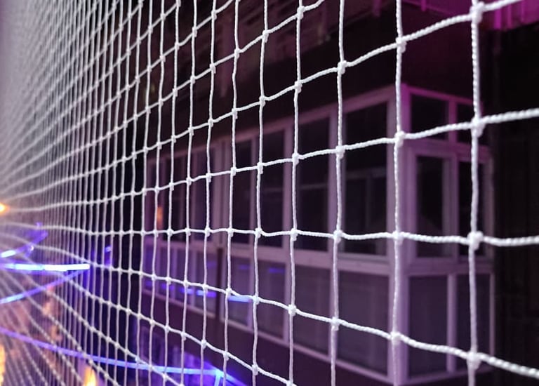 Installation team fitting pigeon nets on a rooftop terrace under bright Chennai sunlight.