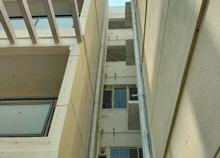 Technician carefully installing safety nets on an apartment duct area.