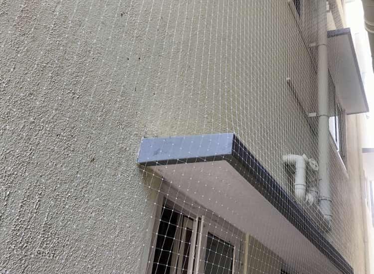 Technician carefully fitting pigeon netting around a rooftop vent in a Kannamangala home.