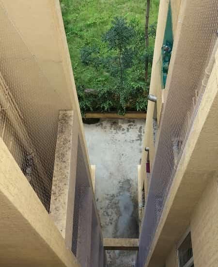 A technician fixing a fallen safety net on a balcony in a busy Whitefield neighborhood.