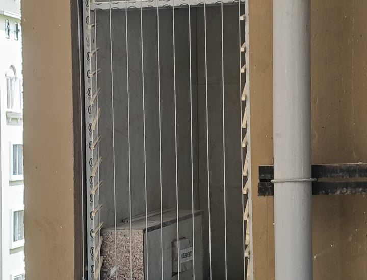 Wide shot of a modern apartment balcony featuring invisible grills with a cityscape backdrop.