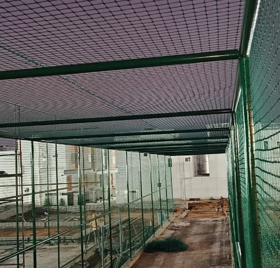 A rooftop cricket net installation with a clear blue sky in Whitefield.
