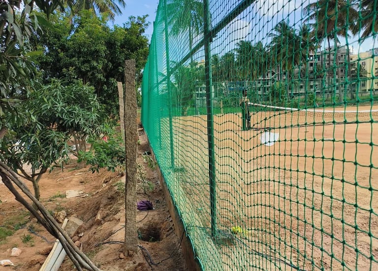 Technicians carefully fixing sports nets on a high-rise building rooftop in Bengaluru.