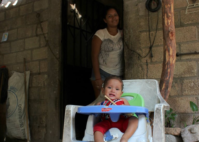 a baby in a chair with a woman standing next to her