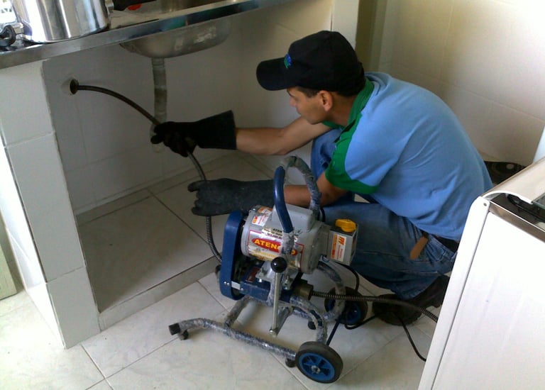 a man in a blue shirt is fixing a sink