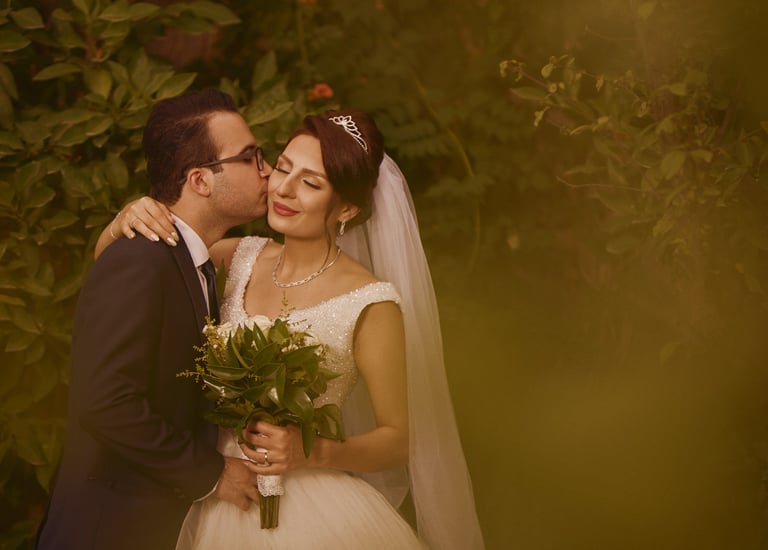 a bride and groom kissing in a garden