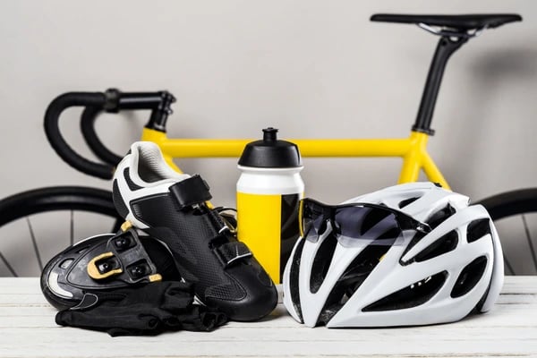 foto raffigurante accessori per bici tra scarpe, casco e borraccia