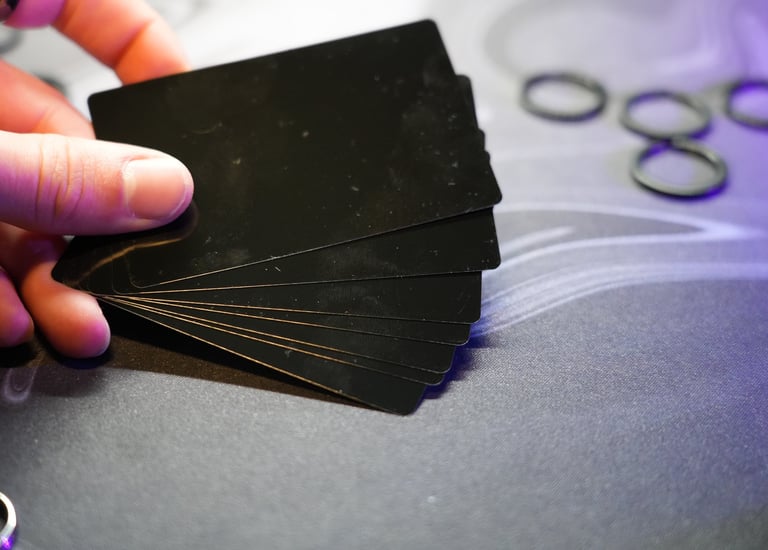 A hand holding a fanned deck of black playing cards on a grey gaming mat.