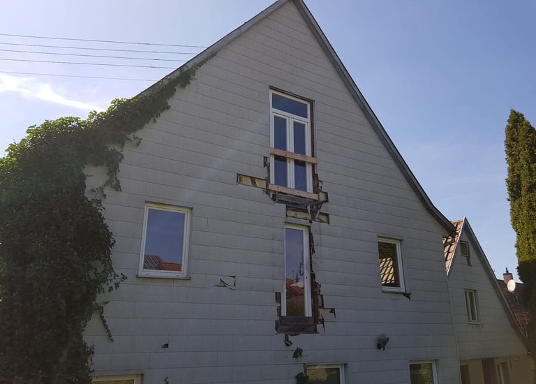 eine alter Fassade mit Löchern in der Verkleidung. Efeu rankt. 