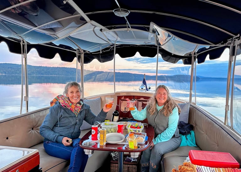 two women sitting at a table with drinks on a sunset eco-friendly electric boat cruise