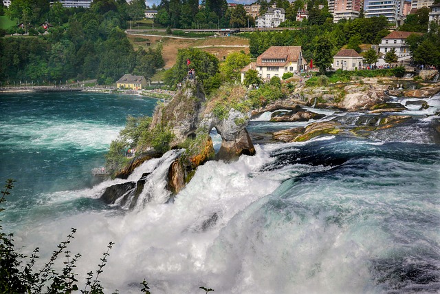 A waterfall in the middle of a river with a view of a city, accessible with our private driver