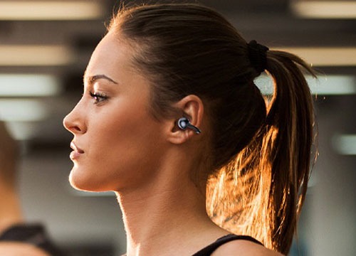 a woman with OWS earphones on a treadmill