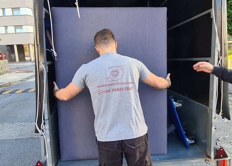 a man is moving a couch into a moving truck
