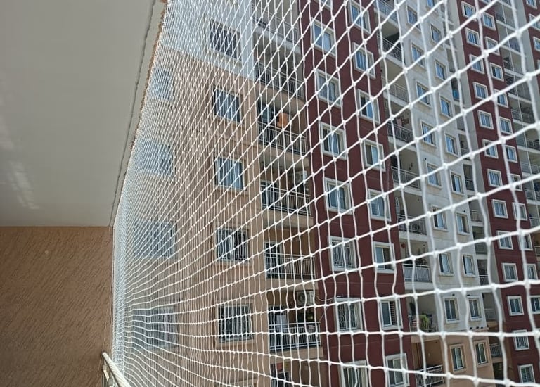 Close-up of a sturdy safety net protecting a playful dog on a balcony.