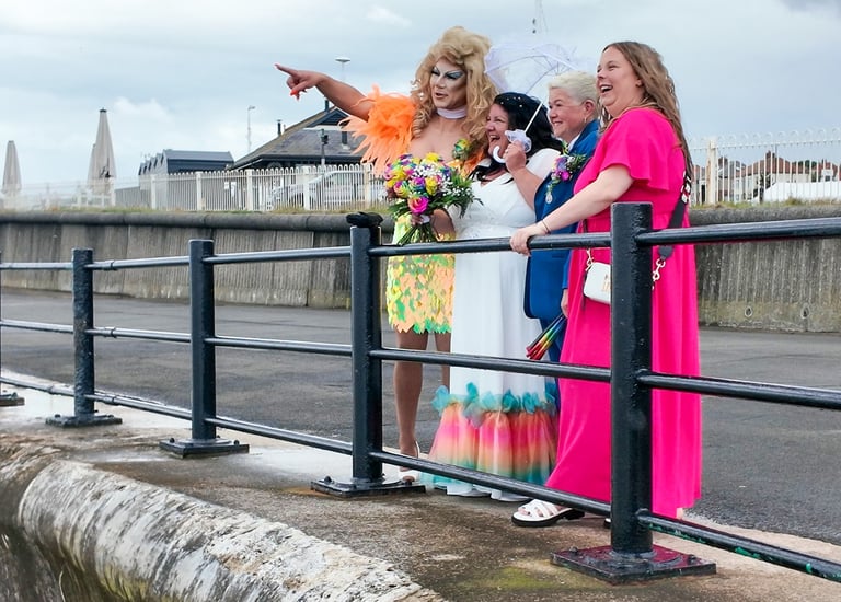 Couple just married with friends laughing at the beach