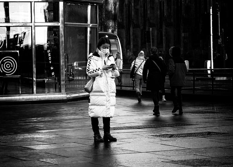 A woman tourist, wearing a face mask, stands at the West End, on her phone. Princes Street, Edinburgh