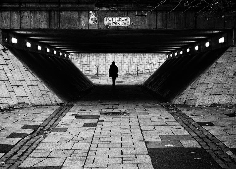A solitary figure, in silhouette, walks through the underpass at Potterow, Edinburgh