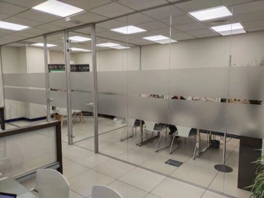 Divisorias para oficinas en cristal laminar de 5+5 mm. con puerta en vidrio templado de 10 mm. y lámina de vinilo opaca eca