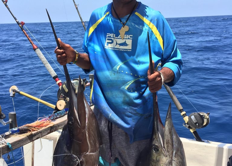 a man holding two fish on a boat