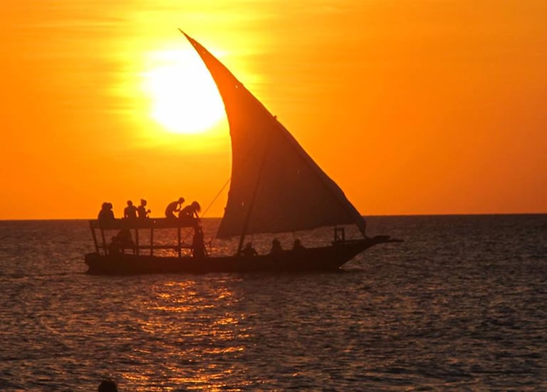 a sailboat sailing on the ocean at sunset
