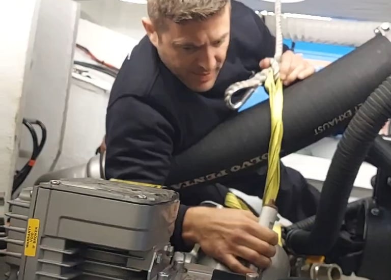 Técnico náutico reparando el motor de una embarcación en un taller especializado en Menorca, con her