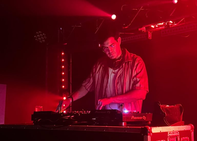 a man in a red shirt is djing in a stage