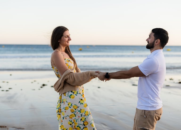 a man and woman holding hands on a beach