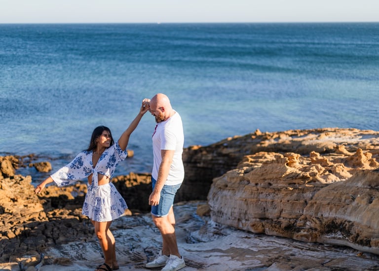 a man and woman dancing on a rocky beach