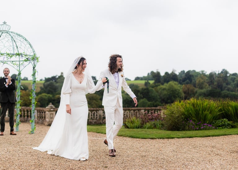a bride and groom walking down a gravel path