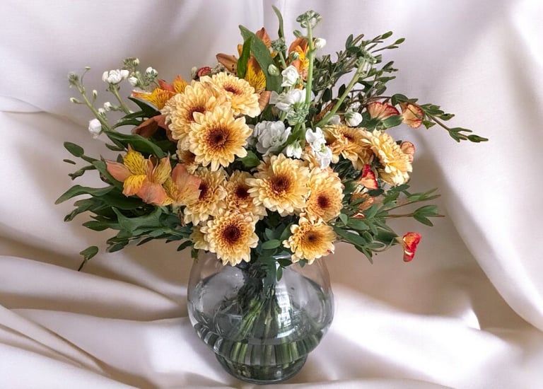a vase with flowers in a vase on a white sheet