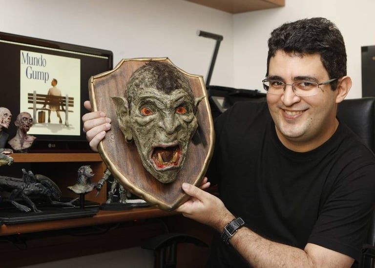 Philipe Kling David segura uma cabeça de Orc decepada enquanto posa na frente do computador