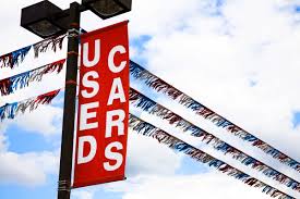 a used cars sign hanging on a light pole