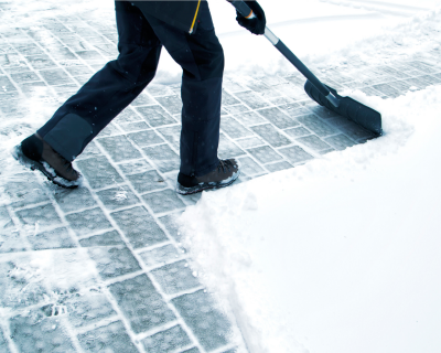Winterdienst beim Schneeräumen auf einem Gehweg