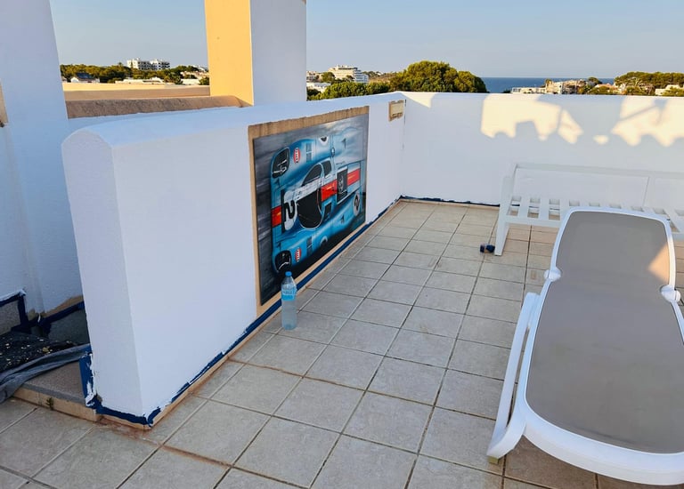 Rooftop terrace featuring a racing car wall mural and a lounge chair with ocean views.